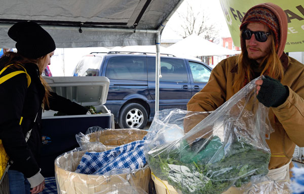 seller bagging aquaponics greens for customer at farmers market