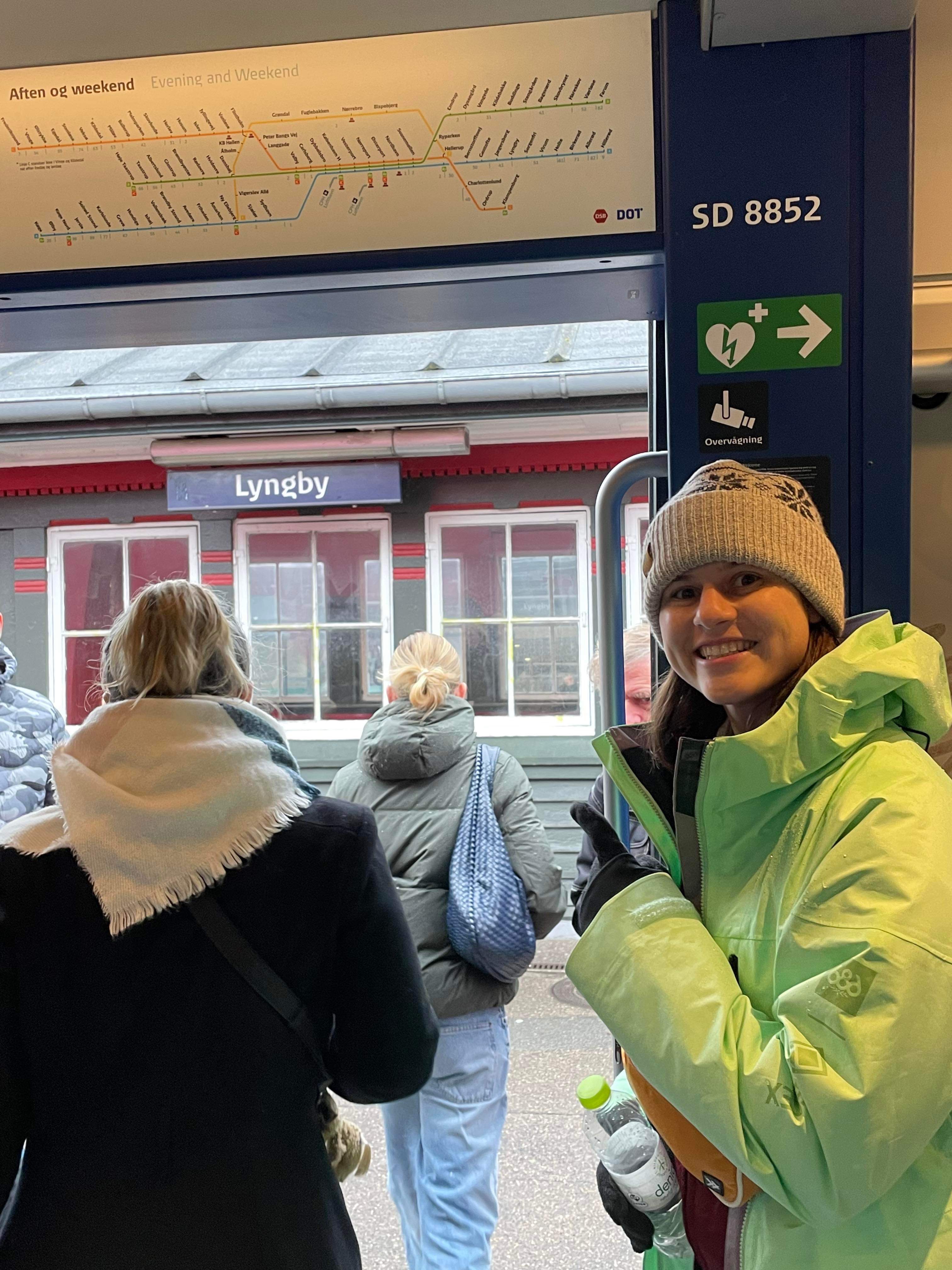 Shayna Keller poses next to a sign for Lyngby near public transport.