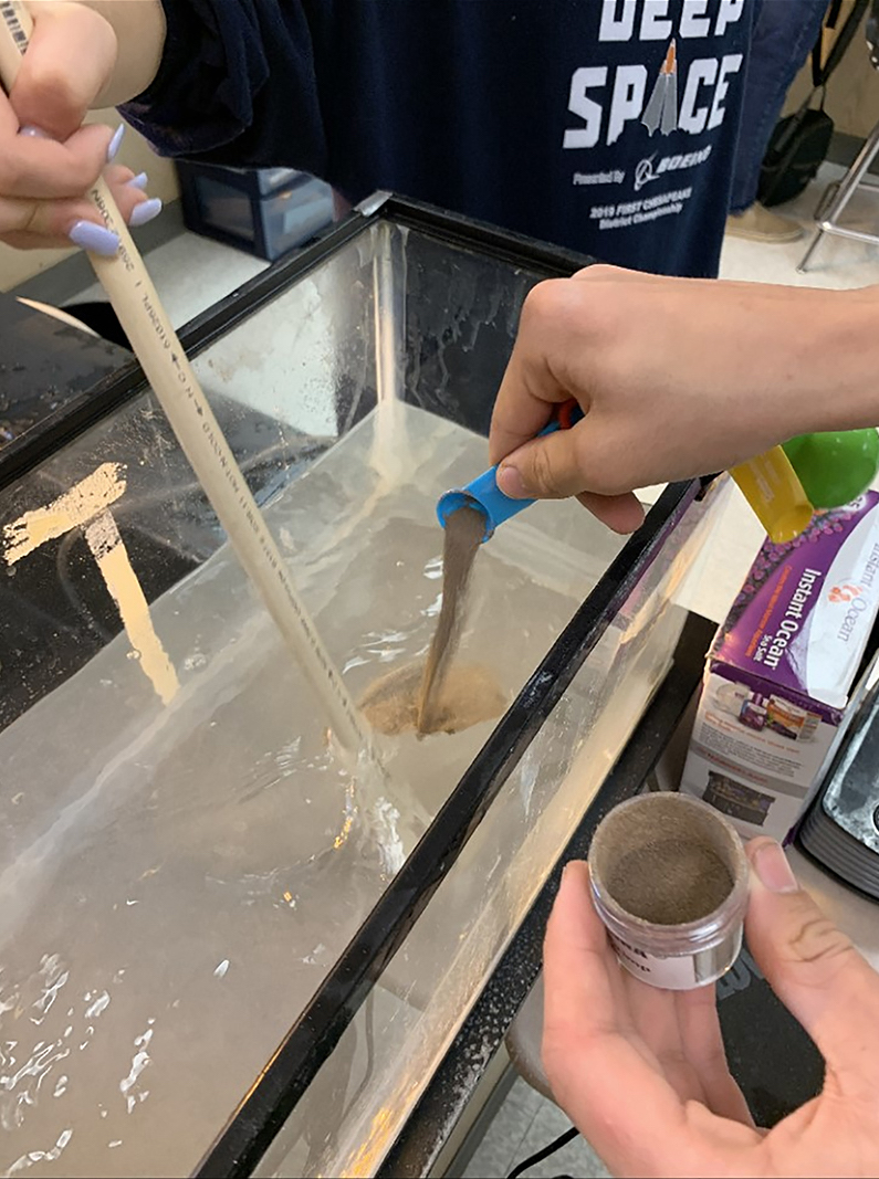 Garrett Kemp from Century High School adds brine shrimp eggs to a saltwater tank. Once hatched, the brine shrimp will be used as food for spotted salamander larvae.