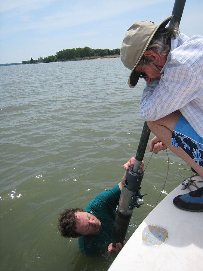 scientics remove core samples of bottom sediment from water