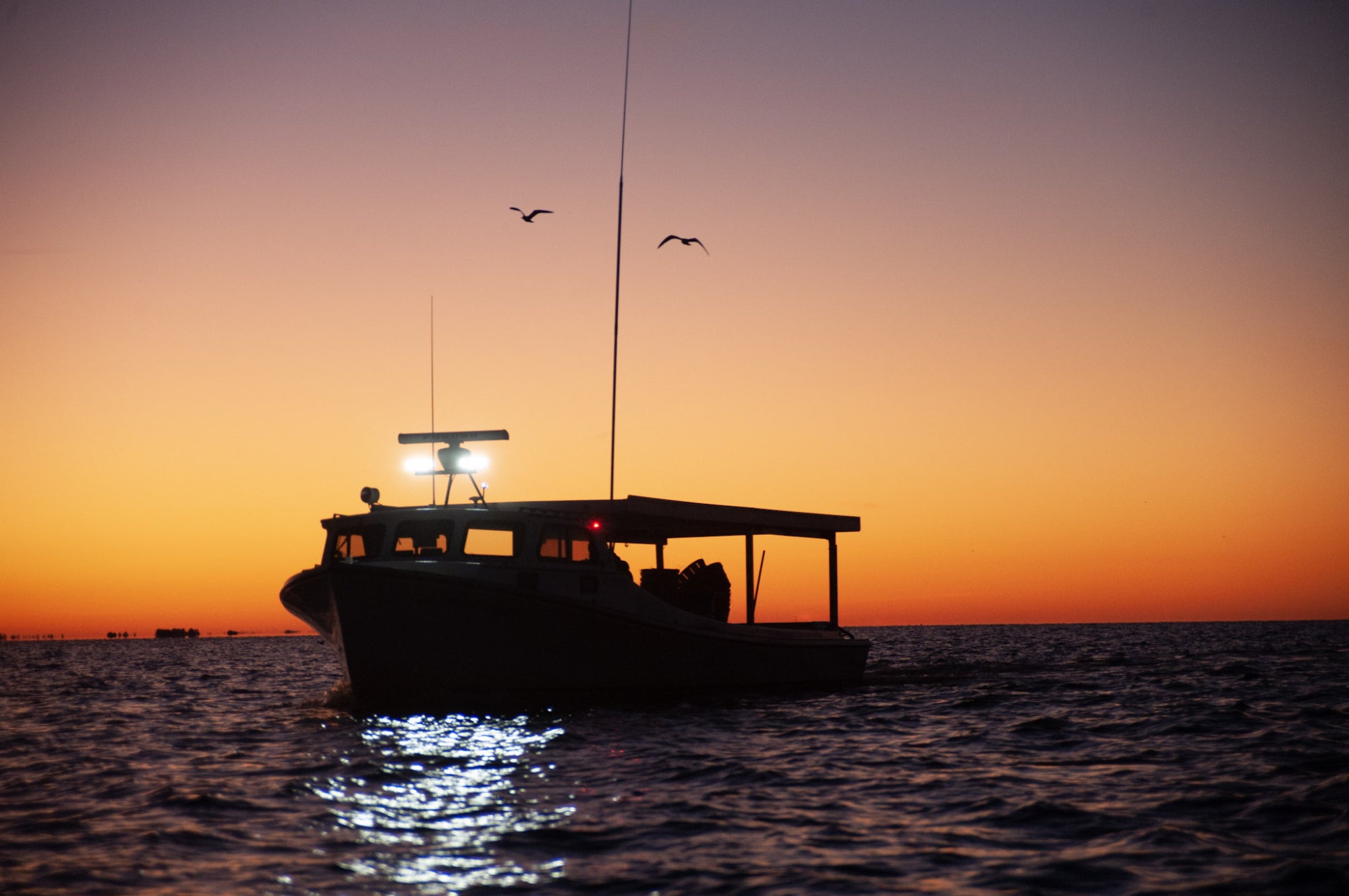 A commercial fishing boat sets off in the Chesapeake Bay at sunrise