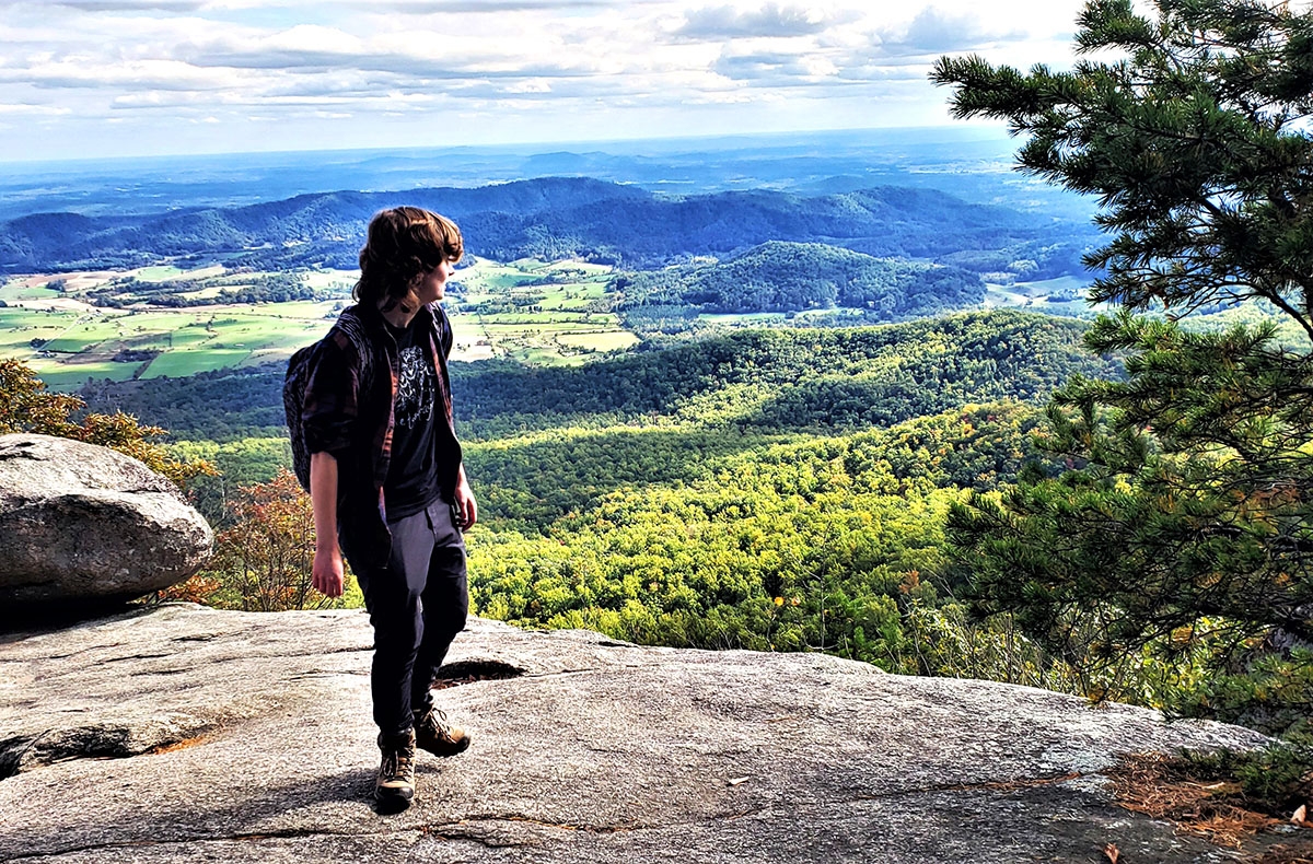 Person standing at a mountain overlook on a hike