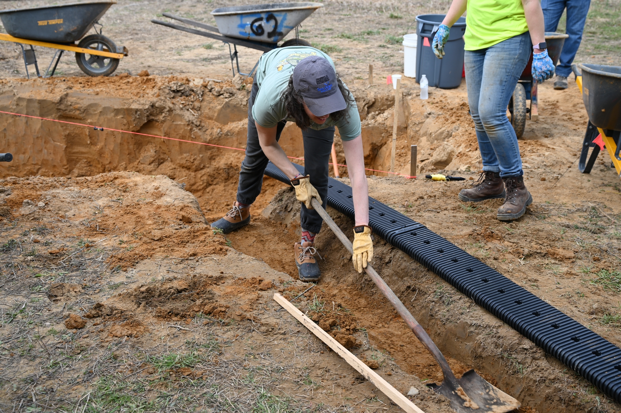 A woman digs a ditch where a pipe will be buried.