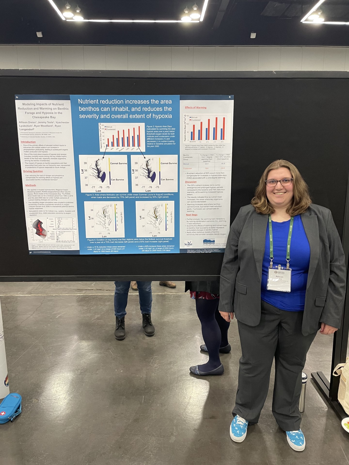 Allison Dreiss smiles standing next to her scientific poster at a conference
