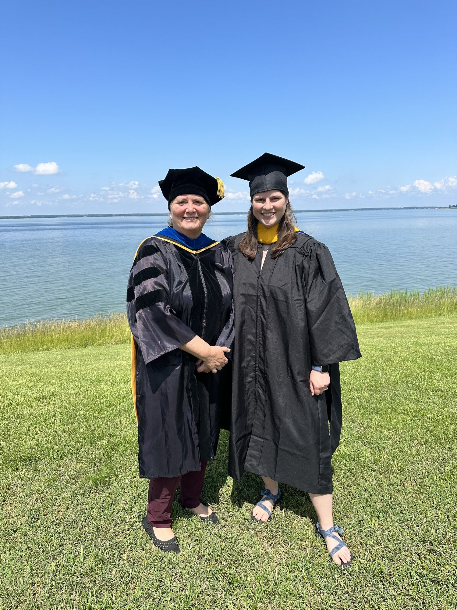 Shayna Keller poses with her advisor, Judy O'Neil, on graduation day. Both women wear caps and gowns.