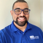 Headshot of man smiling wearing royal blue polo shirt.