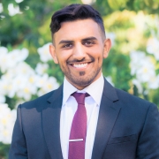 Man in blue suit and red tie in front of trees