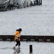 person in a raincoat walking through floodwaters