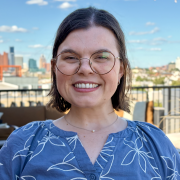 Megan Delatte-Guidry smiling while wearing a blue blouse on a rooftop