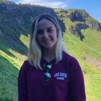 a picture of Mariah Kachmar, standing in front of a mountainside, smiling