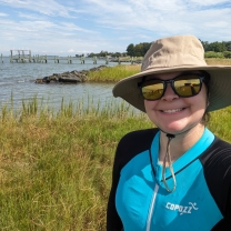 Erika Koontz poses for a photo in front of some wetlands in a living shoreline in Maryland.