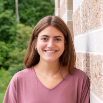 Grace O'Hara smiles, posing next to a wall.