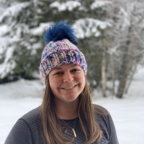 Erika Koontz poses, smiling, in front of snowy trees.