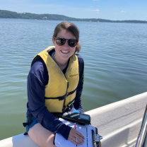 Shayna Keller sits on the edge of a boat, clipboard in hand.