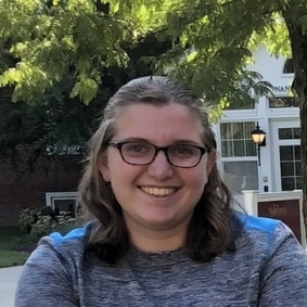 Allison Dreiss smiling wearing glasses and a grey t-shirt.