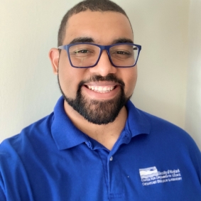 Headshot of man smiling wearing royal blue polo shirt.