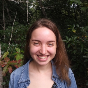 Brunette woman wearing denim shirt smiling while in front of 