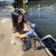 A young woman kneels on a floating platform in the Baltimore Harbor and handles a rack of biofilm discs