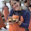 A young woman smiles while wearing waders and holding a large crab.
