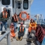 A group of researchers wearing life jackets aboard a research vessel boat on the water