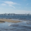 A sandy shoreline of the Chesapeake Bay waters with the Bay Bridge visible in the distance