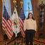 Kayle Krieg stands in front of flags in the Vice President office.