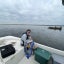 Woman sits on a boat with a clipboard, recording data