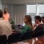 A group of researchers seated at a table listen to a presentation