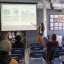 A woman shares a presentation on harvesting stormwater with a small group of people seated in chairs