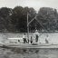 Four men stand on a small boat equipped for examining oyster grounds, as one man sits inside and pilots the boat