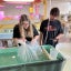 Two students place a bag of tiny salmon into an aquaculture tank in their classroom