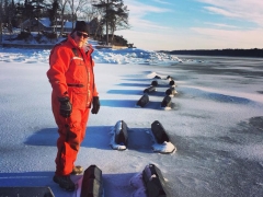 An oyster farm in Maine. The floating cages frozen over and only the cage floats are visable.