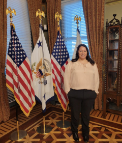 Kayle Krieg stands in front of flags in the Vice President office.