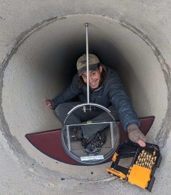 Matthew Wilfong installs a weir and water level logger within the outfall pipe of a dry detention pond.