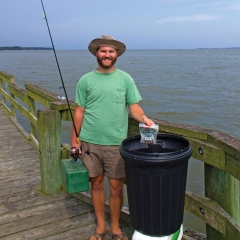 fisher holding bait bag on pier