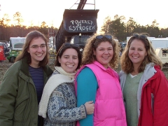 Four women from Horn Point Oyster Hatchery posing in front of a sign that reads "Powered by Estrogen"
