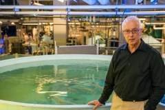 Portrait of Yonathan Zohar standing in front of an aquaculture tank at the Aquaculture Research Center