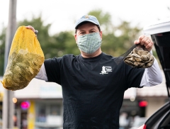 Image of David Vincent in mask holding up a bag of oysters in either hand