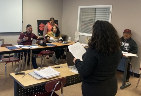 Four adults in a classroom respond to questions from a moderator