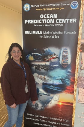 Isabel Butler Viruet stands next to a sign for the Ocean Prediction Center