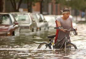 man walking a bicyle through flooded Baltimore street