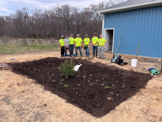 A group of watershed stewards academy students stand next to a newly installed rain garden