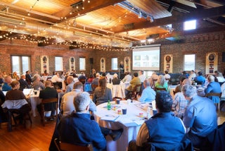 A group of people seated around round tables at a conference