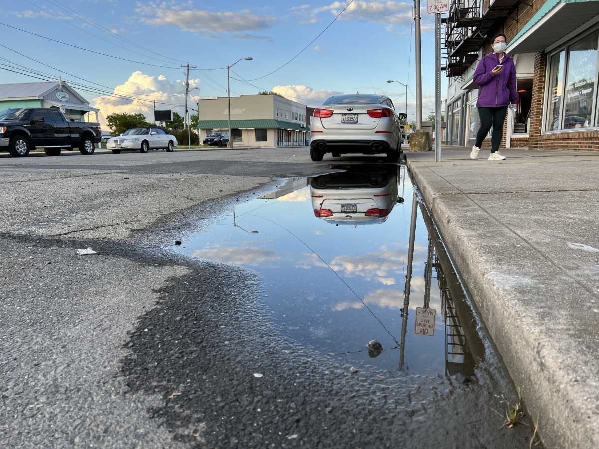 Ju-Ching Huang walks past a car parked on a flooded street.