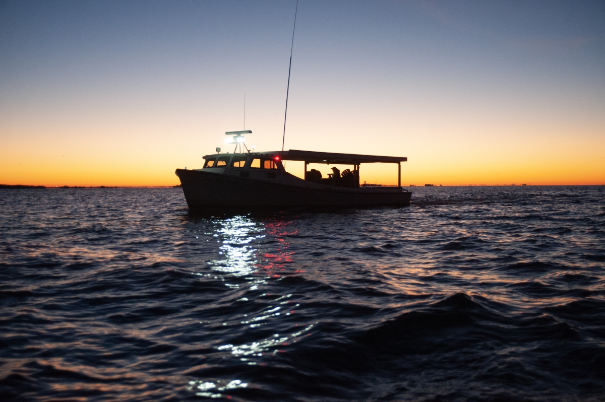 Fishing boat on the water silhouetted by sunrise