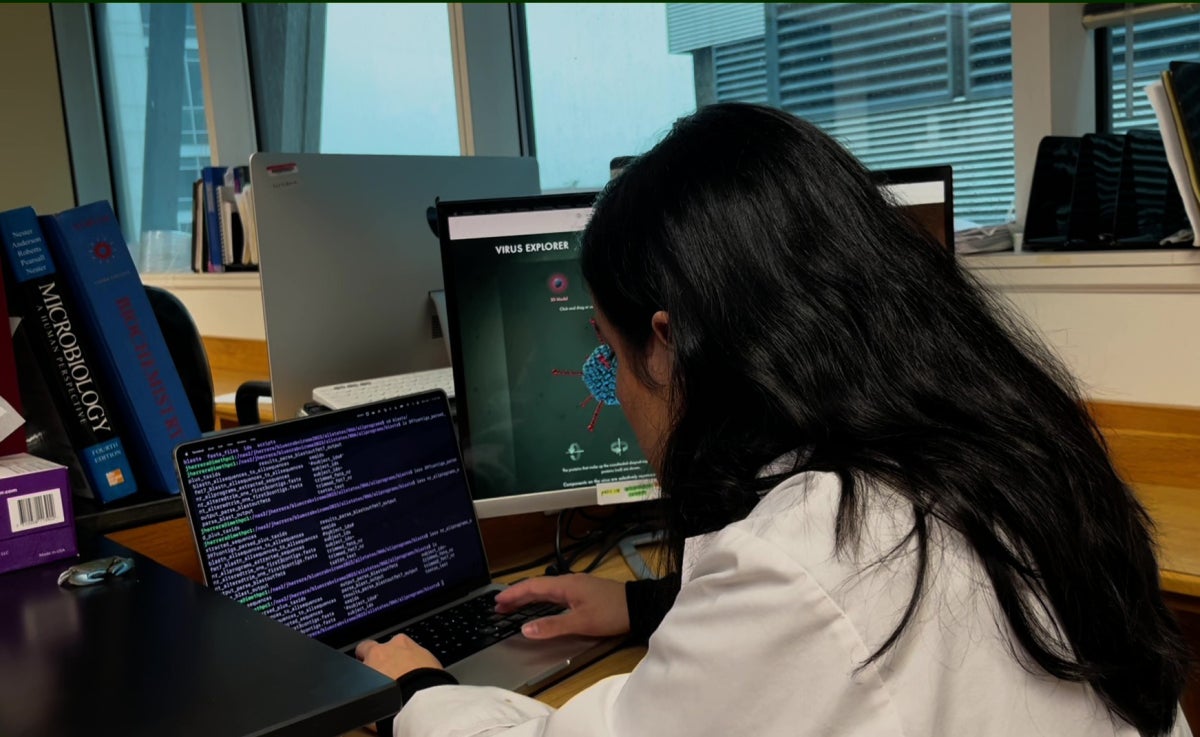 A woman in a lab coat works on a computer in a laboratory