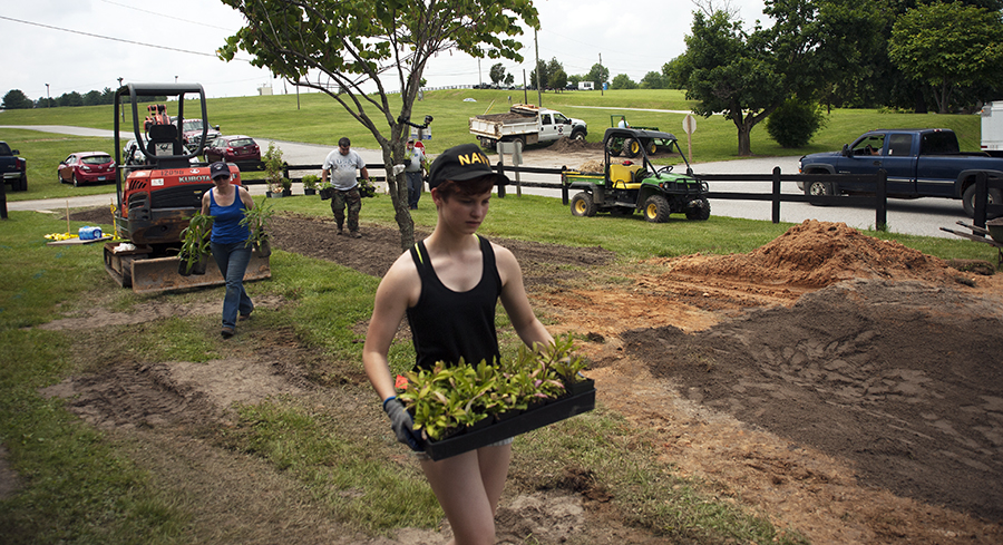 Once the garden’s surface was ready, local volunteers — like Sydney Keys, in the foreground — helped the steward trainees to carry racks of plants to the rain garden for installation. The team bought the plants from nurseries in the area that specialized in growing native plants. Photo: Daniel Pendick